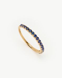 a yellow gold ring with blue sapphire stones on the sides and a thin band around it