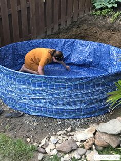 a man in an above ground pool with blue tarp covering it's sides