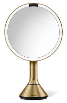 an image of a round mirror on a metal stand with a black base and gold trim