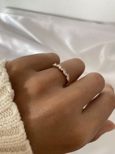 a woman's hand with a diamond ring on top of her left hand, wearing a white knitted sweater