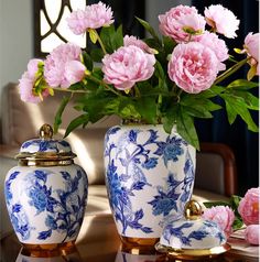 pink flowers are in blue and white vases on a table with other items nearby