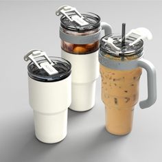 three coffee cups with lids and handles are shown