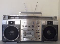 an old fashioned radio with two speakers on it's sides and one is silver