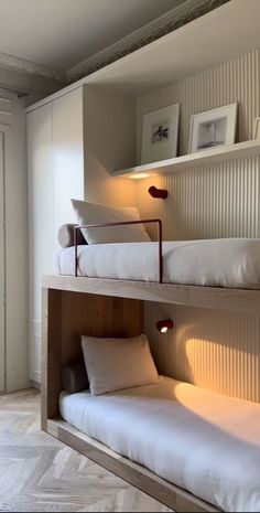 two bunk beds in a room with white walls and wood trimming on the wall