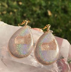 These holographic Teardrop geode earrings made from resin shift from clear gold to a beautiful sparkly rainbow. They are lightweight and won't bother your ears. Please be aware that resin is heat resistant up to 135 degrees. Wearing these earrings in extremely hot temperatures will cause them to be pliable. If this happens, simply place in a cooler location. I am not responsible for any damaged earrings due to extreme heat. Made by Katie Glover Resin Art by Katie 2020 Contact me on my Instagram Unique Iridescent Teardrop Earrings, Iridescent Teardrop Jewelry For Gift, Gold Resin Dangle Jewelry, Iridescent Drop Earrings For Gift, Iridescent Teardrop Hypoallergenic Jewelry, Iridescent Jewelry With Natural Inclusions For Gift, Gold Resin Drop Earrings, Clear Drop Jewelry For Parties, Clear Long Drop Jewelry As Gift