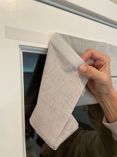 a person is holding up a piece of cloth to the side of a window sill