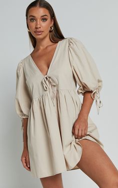 Turn heads in our Rosita Mini Dress! This tie front puff sleeve dress in stone is the perfect addition to your casual weekend activities. Made from comfortable cotton, this V-neck mini dress features 3/4 sleeves for a chic and stylish look. Its neutral color makes it easy to pair with any accessories or shoes, giving you endless options for creating different outfits. Whether you're meeting friends for brunch or running errands around town, the Rosita Mini Dress will keep you looking effortlessl Cotton V-neck Puff Sleeve Dress For Brunch, Beige V-neck Cotton Mini Dress, Beige Cotton V-neck Mini Dress, Doc Fits, Nursing Outfits, Outfits For Spain, Linen Casual Dress, Splendid Dress, Weekend Activities