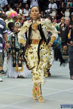 a woman dressed in an elaborate costume walking down the street with other people behind her