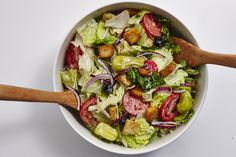 a salad in a white bowl with wooden spoons on the side, ready to be eaten