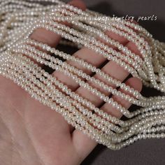 a hand holding several strands of white pearls