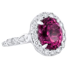 Behold, a ring that's bound to steal your heart and captivate the eyes of all who gaze upon it. This stunning masterpiece is a true testament to the beauty that can be found in the world of fine jewelry. At its heart lies a vibrant 6.04-carat oval cut Raspberry Garnet, a gemstone that embodies passion, vitality, and love. Its deep, rich hue is as unique as it is mesmerizing, making it the perfect symbol of individuality and creativity. The Raspberry Garnet takes center stage, embraced by a delic 2 Carat Ring, 2 Carat Diamond Ring, Pear Shaped Diamond, Center Stage, 2 Carat, Jewelry Rings Engagement, White Diamonds, Earings Piercings, Oval Cut