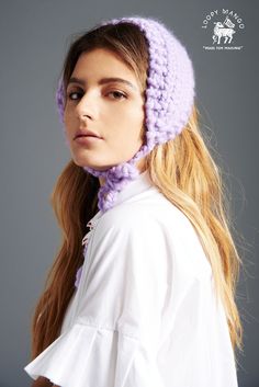 a woman wearing a purple knitted hat and white shirt is posing for the camera