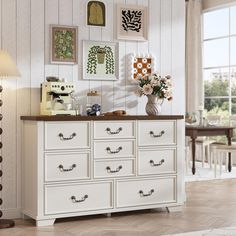 a white dresser with flowers and pictures on the wall