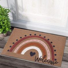 a welcome mat with a rainbow and heart on the front door sill next to a potted plant