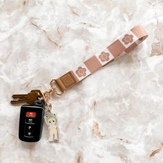 a keychain with two keys attached to it on a marble counter top next to a cell phone