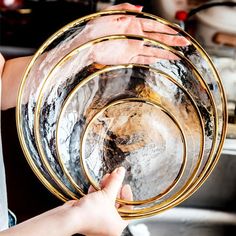 two people holding plates in their hands over a sink with water running down the side