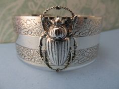 "Myelegantthings presents a gorgeous Scarab Beetles cuff.bracelet. I made these in 1970's for my jewelry line, \"Angelina Verbuni Designs\" 1 inch engraved cuff opens in back The scarab is about 1 inch. 18 K matt gold plating over brass All brass vintage findings. Chic! I have other bangles I've made also with bumble bees, panthers, butterflies and lions and lots of necklaces to match also. Available in silver or gold All USA made" Lots Of Necklaces, Scarab Jewelry, Egyptian Revival Jewelry, Scarab Bracelet, Engraved Cuff, Egyptian Scarab, Egyptian Style, Bumble Bees, Egyptian Revival