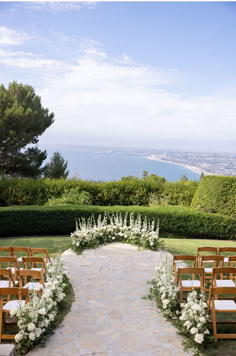 an outdoor wedding ceremony setup with white flowers and greenery on the aisle, overlooking the ocean