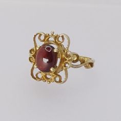 Indulge in the timeless beauty of the Art Nouveau era with this exquisite vintage ring. Meticulously crafted from hallmarked 9ct yellow gold, this ring features a lustrous Cabochon garnet gemstone that exudes vintage charm, making it a perfect addition to any outfit. Key Features: - Metal: Hallmarked 9ct Yellow Gold - Gemstone: Cabochon Garnet - Garnet Dimensions: Approximately 7.8mm by 6.4mm - Ring Size: UK Size M/N - Weight: 2.8 grams - Head Dimensions: Approximately 15.1mm by 13.2mm This ring Antique Ruby Rings With Polished Finish, Classic Gold Ruby Cabochon Ring, Classic Yellow Gold Cabochon Ruby Ring, Antique Yellow Gold Ruby Ring With Polished Finish, Classic Yellow Gold Ruby Cabochon Ring, Red Cabochon Ruby Ring In 14k Gold, 14k Gold Red Cabochon Ruby Ring, Yellow Gold Garnet Ring With Polished Finish, Formal Red Birthstone Ring With Polished Finish