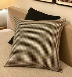 two framed pictures hang on the wall behind a couch with a black and white checkered pillow