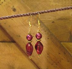 two red beads are hanging from a rope on a wooden surface with other items in the background