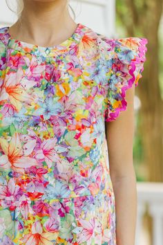 Say hello to this colorful floral babydoll dress with its charming rickrack detailing! Bursting with stunning colors, this dress is sure to brighten your day. The ruffled cap sleeves add a touch of femininity, making it perfect for any occasion. Pair it with sneakers for a fun day out or dress it up with heels for a chic, sophisticated look! Round neckline Button keyhole back Ruffled cap sleeves Colorful floral print Rickrack detailing Babydoll cut No stretch Baileigh is wearing the small. Colorful Ruffled Dresses For Summer, Multicolor Dresses With Ruffles And Flutter Sleeves, Cap Sleeve Dresses With Ruffles For Garden Party, Multicolor Ruffled Straps Dress For Garden Party, Colorful Floral Print Short Sleeve Dress, Multicolor Dress With Ruffled Straps For Garden Party, Multicolor Dresses With Ruffled Straps For Garden Party, Multicolor Flutter Sleeve Dresses For Spring, Whimsical Floral Print Dress With Short Sleeves