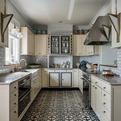 a kitchen with white cabinets and black and white tile flooring on the walls, along with stainless steel appliances