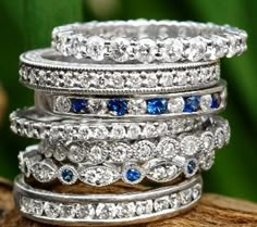 a stack of rings sitting on top of a piece of driftwood with blue and white stones