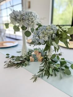 blue flowers and greenery are on the table