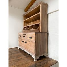 a large wooden cabinet sitting on top of a hard wood floor next to a white wall