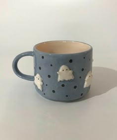 a ceramic cup with some little white clouds on it's side and black dots around the rim