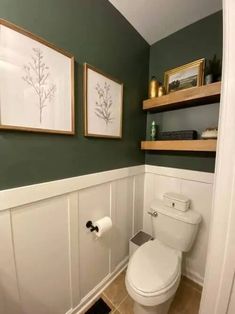 a white toilet sitting in a bathroom next to two framed pictures