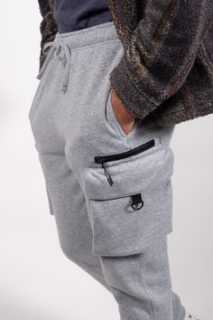 Introducing the Zip Cargo Pocket Fleece Sweatpants in Carpenter Style, crafted for the perfect combination of style and functionality. Made from 100% Poly Fleece, these sweatpants offer ultimate comfort and warmth. With a multitude of pockets including side pockets, side zip pockets, flap cargo pockets, and a back pocket, you'll have plenty of storage options for your essentials. The elasticated drawstring waist ensures a secure and customizable fit. Whether you're running errands or going for a Fleece Sweatpants, Cargo Pocket, Mens Sweatpants, Running Errands, Drawstring Waist, Side Zip, Heather Grey, Zip Pockets, Brooklyn