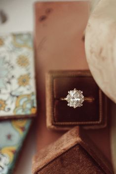 an engagement ring sitting on top of a wooden box next to other jewelry boxes and accessories