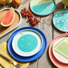 a table with plates and fruit on it, including watermelon, grapefruit, melon