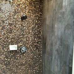 the shower head is next to the tiled wall in this bathroom with silver and gold mosaic tiles