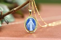 "Miraculous Medal cameo pendant, 18 k gold plating over sterling silver, Our Lady of grace necklace pendant, blue agate Virgin Mar pendant  This miraculous medal cameo pendant is made with 18 k gold platted sterling silver 925  and blue Agate paste combined with resin glue. Medal is made with two parts : - Sterling silver frame with gold plating  - Blue agate Our Lady of Grace centrepiece  On sterling silver frame in front is written in French language: \" O Marie concue sans peche priez pour no Miraculous Medal Pendant Gift, Elegant Sterling Silver Necklace With Miraculous Medal, Miraculous Medal Pendant For Memorial, Elegant Miraculous Medal Jewelry Gift, Elegant Miraculous Medal Jewelry For Gift, Gold Plated Miraculous Medal Jewelry As Gift, Memorial Miraculous Medal Pendant Jewelry, Elegant Commemoration Jewelry With Charms, Elegant Miraculous Medal Jewelry