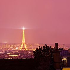 the eiffel tower lit up at night in paris, france with pink sky