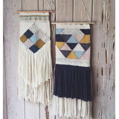 two woven wall hangings with different colors and patterns on them against a wooden background