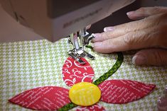 a woman is using scissors to sew a flower on a piece of fabric that has been cut