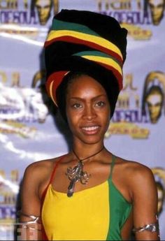 a woman in a colorful dress and headdress smiles for the camera at an awards event