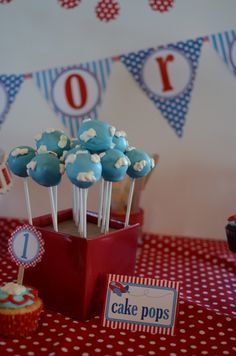 blue and white cake pops are in a red cupcake holder on a table with polka dots