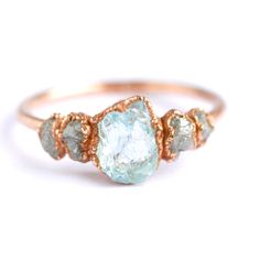 a gold ring with an aqua blue topazte and two white diamonds on it