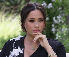 a woman sitting on a chair with her hand under her chin and looking at the camera