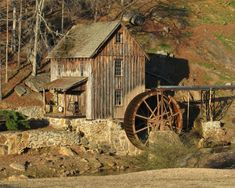 an old water mill sits on the side of a hill