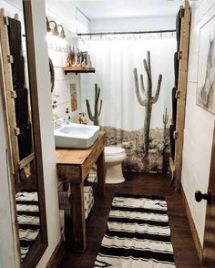 a bathroom with a cactus shower curtain next to a white sink and wooden flooring