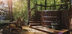 a hot tub sitting on top of a wooden deck next to a tree filled forest