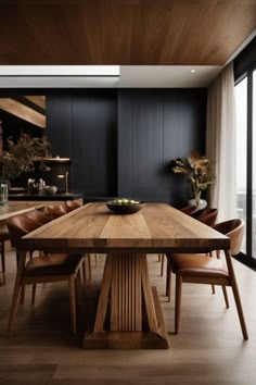 a wooden table surrounded by brown leather chairs in a room with black walls and wood flooring