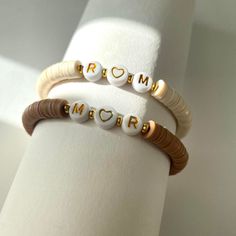 two bracelets with the word prom written in gold and white beads on each wrist