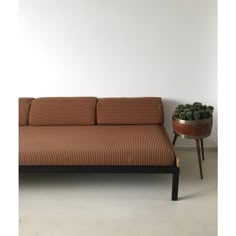 a couch sitting next to a table with a potted plant on top of it